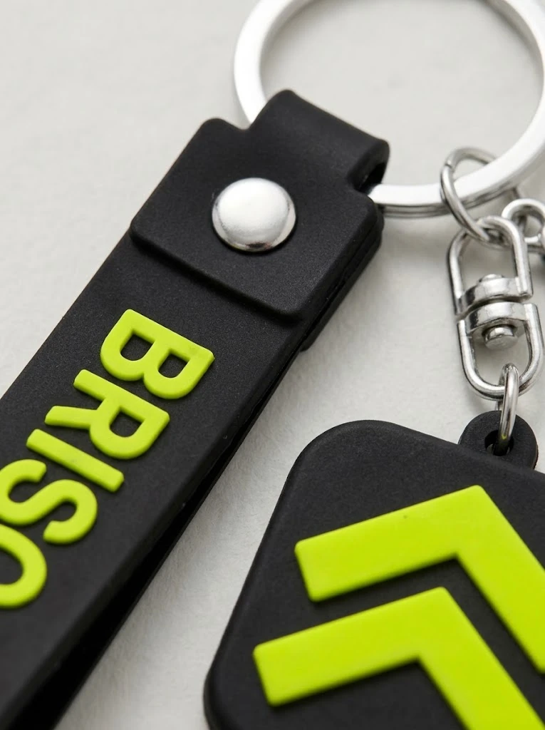 Gros plan du Porte-clé Strap : dragonne en caoutchouc noir, BRISCARD moulé en relief lime.
